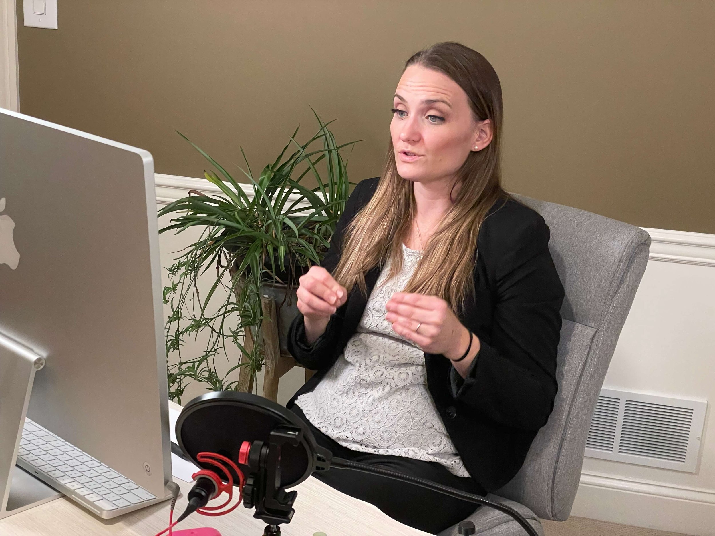 a woman sits in front of a microphone and a laptop